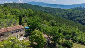 A stone building with a tiled roof, surrounded by lush greenery and hills in the background. - Nice home in Skabici with WiFi (Skabici)