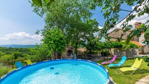 A swimming pool with a view of the countryside, surrounded by colorful lounge chairs and a stone building. - Nice home in Skabici with WiFi (Skabici)