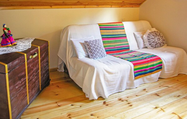 Una habitación acogedora con una cama cubierta por un edredón a rayas, un aparador de madera y un pequeño adorno encima.