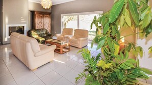 A living room with a sofa, two armchairs, a coffee table, and a fireplace. There are large windows and a plant in the foreground. - Amazing home in Milhaud with WiFi (Milhaud)
