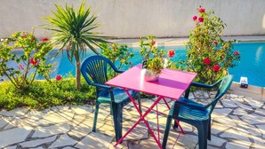A patio with a table and chairs, a potted plant, and a pool. - Amazing home in Milhaud with WiFi (Milhaud)