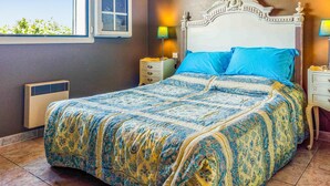 A bedroom with a large bed, two bedside tables, a nightstand, a window, and a wall-mounted heater. - Amazing home in Milhaud with WiFi (Milhaud)