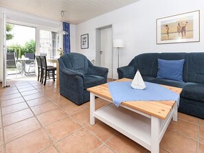 A living room with two sofas, a coffee table, and a dining area with chairs and a table.