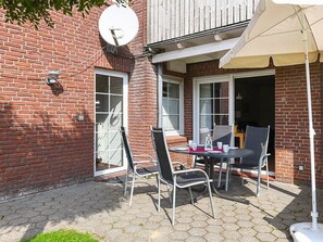 Un espace patio avec une table et des chaises, une antenne parabolique et un coin salon abrité.