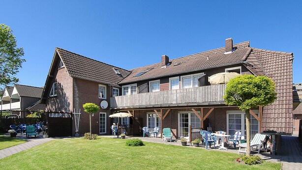 Een gebouw met twee verdiepingen, een balkon, een terras en een verzorgd gazon.