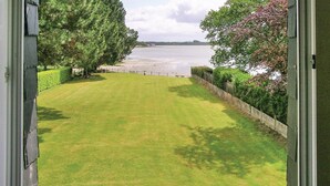 A well-maintained lawn with a view of a body of water and a distant building. - 4 bedroom amazing home in Locoal-Mendon (Locoal-Mendon)
