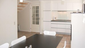 A modern kitchen with white cabinets, a black dining table, and white chairs. - Gorgeous home in Blåvand with sauna (Blåvand)