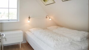A bedroom with a bed, a nightstand, and a window. - Gorgeous home in Blåvand with sauna (Blåvand)