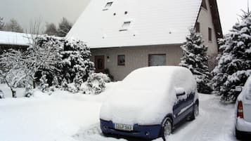 Ein Wohngebäude mit verschneitem Dach und geparkten Autos.