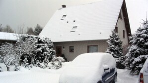 A residential building with a snow-covered roof and parked cars. - Double room - Family Pension & Apartments Fischer-Haus (Trassenheide)