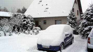 A residential building with a snow-covered roof and parked cars.