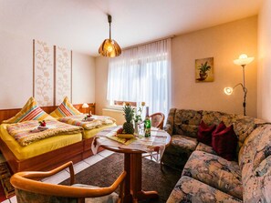 Una sala de estar acogedora con un sofá, una butaca, una mesa y una lámpara.