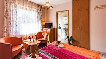 A hotel room with a bed, a sofa, a TV, a desk, and a wardrobe.