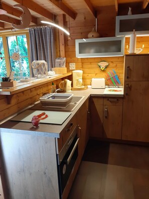 Cocina de cabaña de madera con encimera de madera, un fregadero, un microondas y una ventana con cortinas.