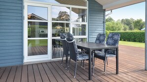 An outdoor patio with a table and chairs, a sliding glass door, and a view of a garden. - Stunning home in Knebel with sauna (Knebel)