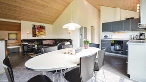 A modern kitchen with a dining area, featuring a large island, grey cabinets, and a hanging light fixture. - Stunning home in Knebel with sauna (Knebel)