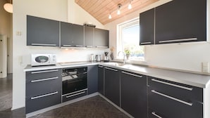 A modern kitchen with dark cabinets, a built-in oven, and a microwave. - Stunning home in Knebel with sauna (Knebel)