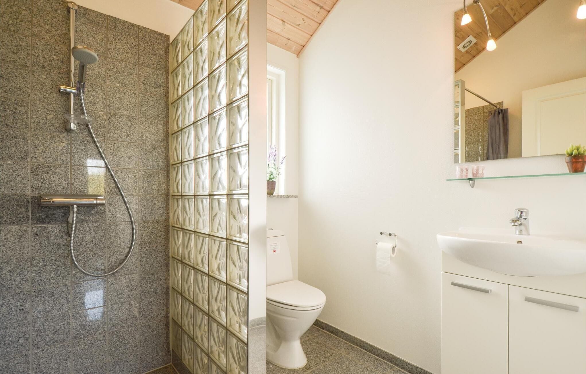 Un baño con ducha, inodoro, lavabo y espejo.