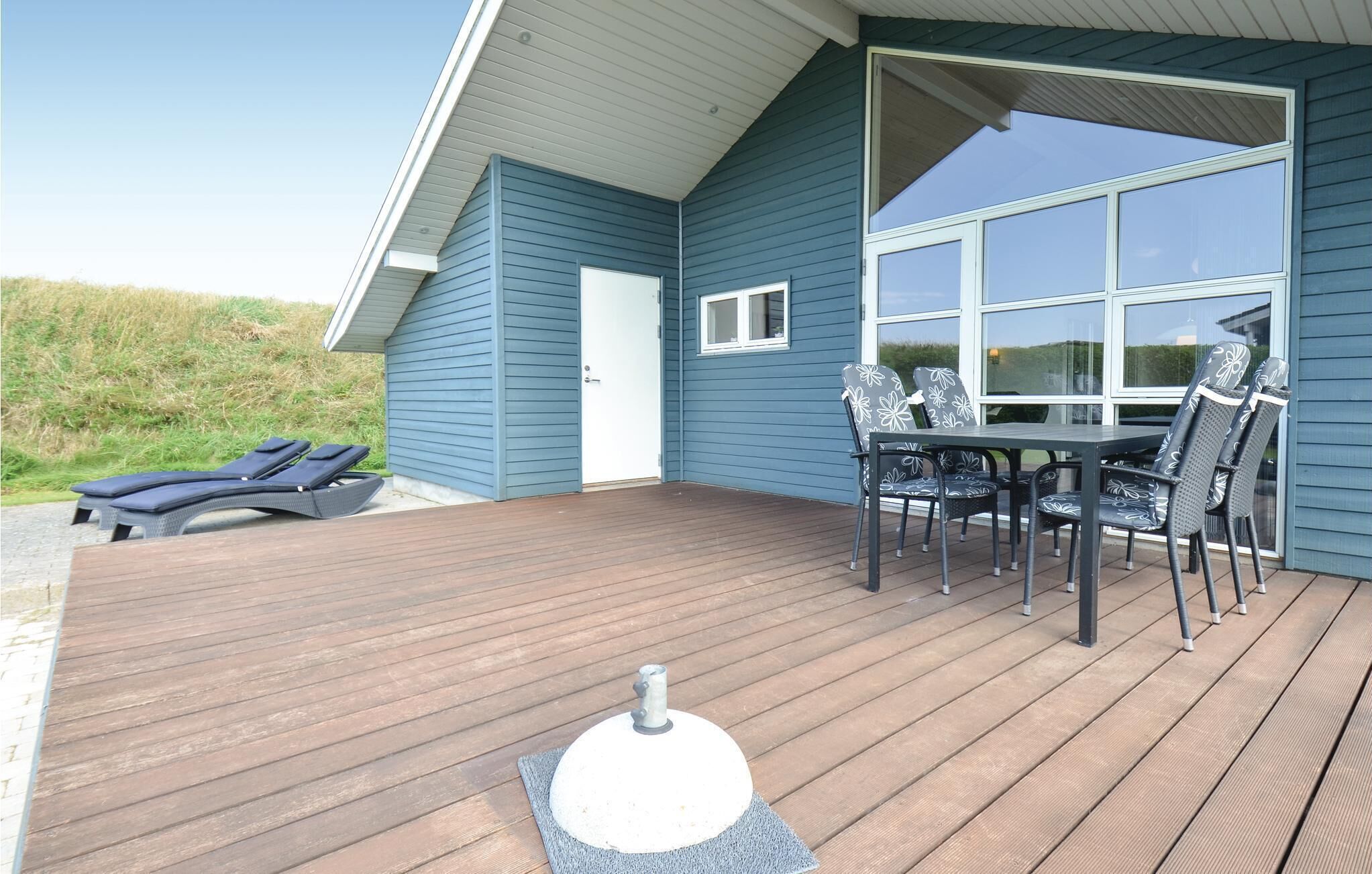 A deck with a table and chairs, a small window, and a door.