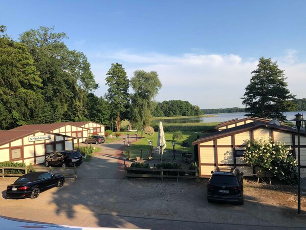 A hotel with a gravel driveway, parked cars, and a view of a lake.
