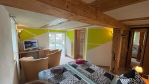 Een slaapkamer met een bed, een bureau met een computer, een stoel en een douchegedeelte.