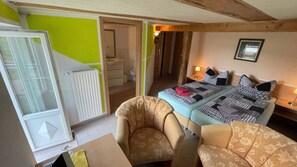 A bedroom with a bed, a chair, a radiator, and a bathroom visible through an open door. - 06 double room with terrace and view of the Dobbertiner See - Insel-Hotel Dobbertin (Dobbertin)
