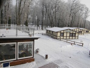 A snow-covered building with a balcony, a wooden fence, and a sign that reads 'Ferienhäuser.'