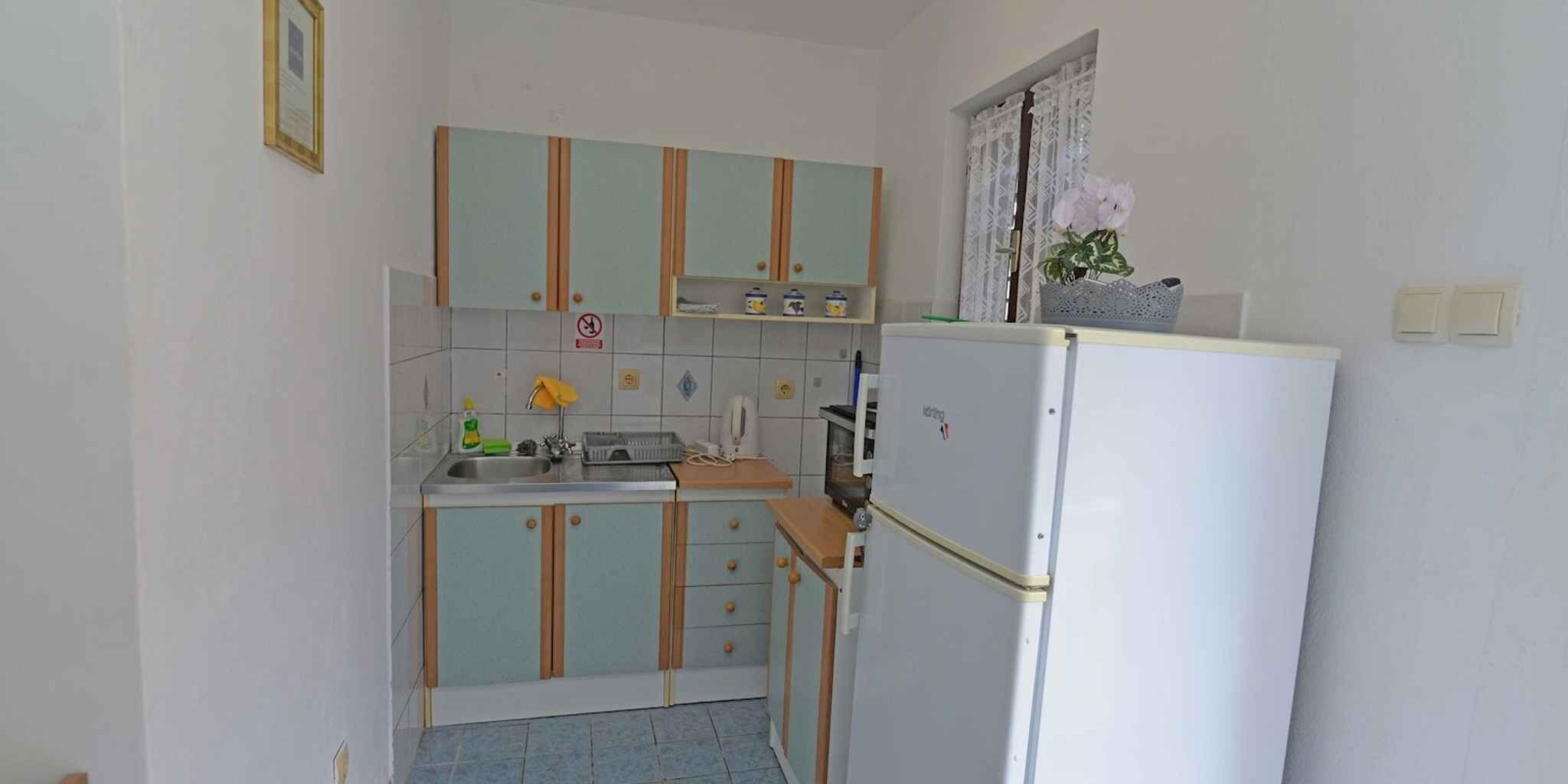 A small kitchen with a sink, cabinets, and a refrigerator.