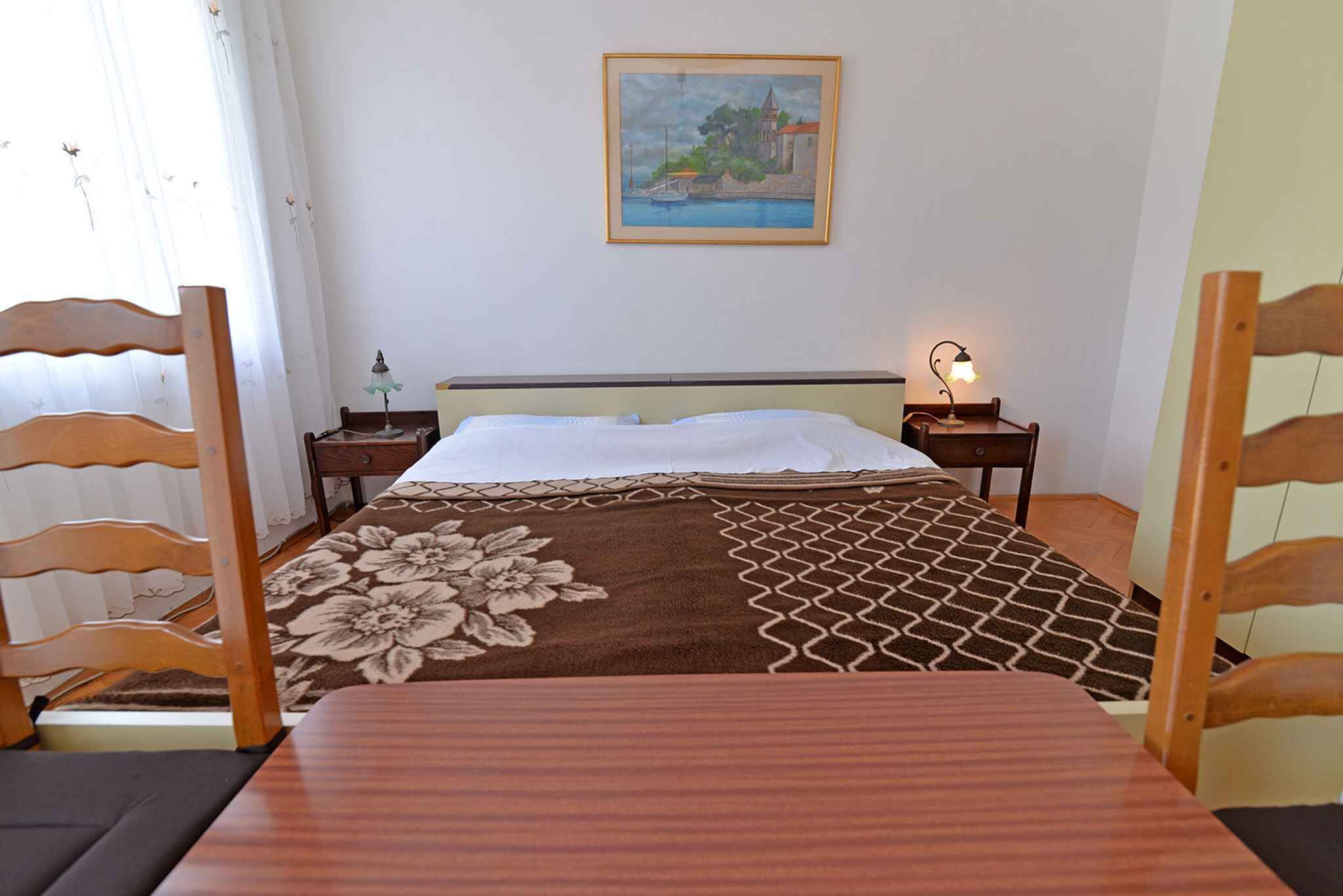 Una camera da letto con un letto, due comodini, una lampada, un quadro appeso e una finestra con tende.