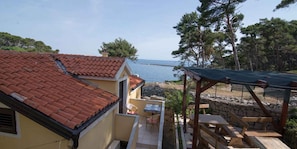 Ein Küstenanwesen mit Ziegeldach, einer Terrasse mit Tisch und Stühlen und Blick auf das Meer.