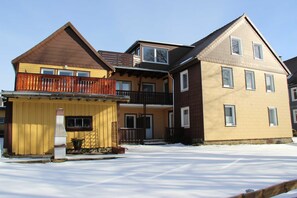 A two-story building with a balcony, a porch, and a snow-covered ground. - Vacation apartment Bianca - House Reese (Clausthal-Zellerfeld)