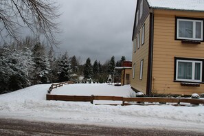 A residential building with a snow-covered yard and a wooden fence.