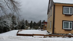 A residential building with a snow-covered yard and a wooden fence.