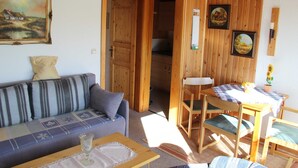 A cozy room with a sofa, a small table, and a dining area with chairs.