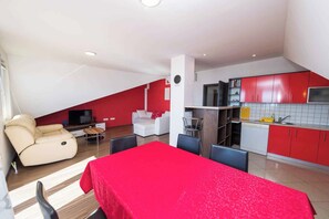 A compact living space with a kitchenette, a dining area, and a seating area with a sofa and a TV.