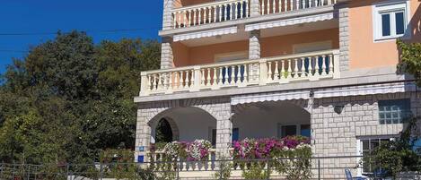 A multi-story building with balconies, a garage, and potted plants.