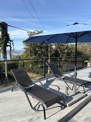Two lounge chairs with a large umbrella, a concrete floor, and a view of a body of water. - Holiday apartment with panoramic view (Dramalj)