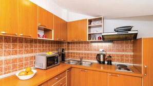 Una cocina con armarios de madera, microondas, hervidor y cafetera sobre el mostrador.
