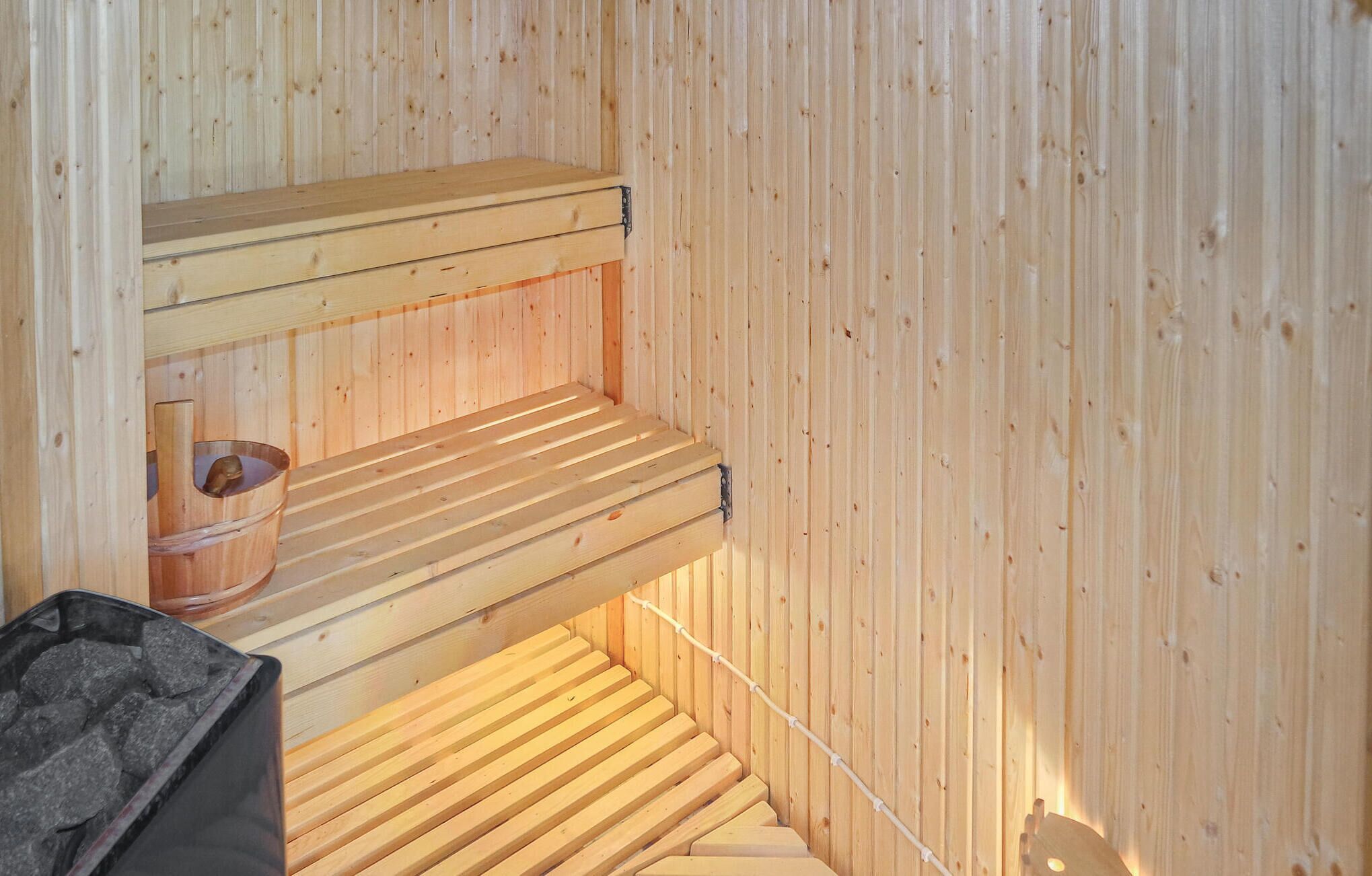 Una sauna con bancos de madera y un pequeño balde de madera.