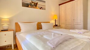 Habitación de hotel con una cama grande, dos mesitas de noche con lámparas, un armario y un cuadro en la pared.