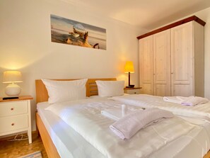 Habitación de hotel con una cama grande, dos mesitas de noche con lámparas, un armario y un cuadro en la pared.