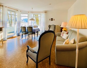 Ein Wohnzimmer mit einer Couch, Sesseln, einem Tisch und einer Lampe.