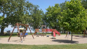 A playground with a swing set, slide, and climbing structure. - Studio with covered terrace and billiards, near the harbour (Balatonboglár)