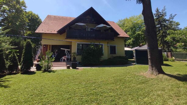 A two-story house with a red-tiled roof, a balcony, and a well-maintained lawn. - Studio with covered terrace and billiards, near the harbour (Balatonboglár)