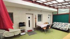 A room with a table and chairs, a microwave, a door, and a window. - Studio with covered terrace and billiards, near the harbour (Balatonboglár)