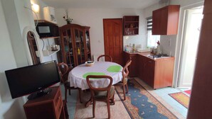 A compact living space with a dining area, a kitchen, and a TV. - Studio with covered terrace and billiards, near the harbour (Balatonboglár)