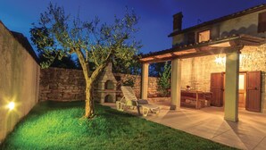 A patio area with a stone wall, a tree, and a barbecue grill. - Pet friendly home in Filipana (Filipana)