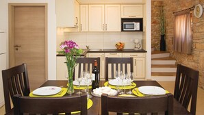 A dining area with a table set for four, a vase with flowers, and a kitchen in the background. - Pet friendly home in Filipana (Filipana)