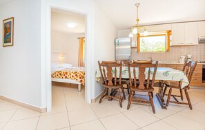 A compact kitchen with a dining table and chairs, a refrigerator, and a window with a view. - 2 bedroom lovely apartment in Vodice (Vodice)