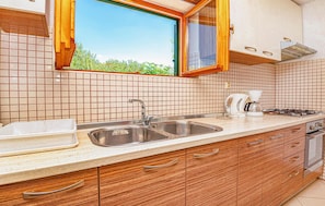 A kitchen with a sink, stove, and window overlooking greenery. - 2 bedroom lovely apartment in Vodice (Vodice)